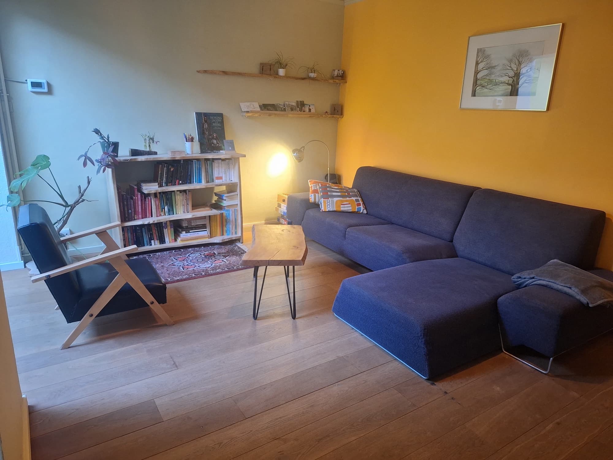 De praktijkruimte met zetel, leesstoel en boekenkast